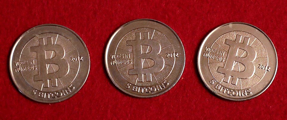 Three 2012 Casascius 5 Bitcoin Bitnickel coins photographed on red fabric